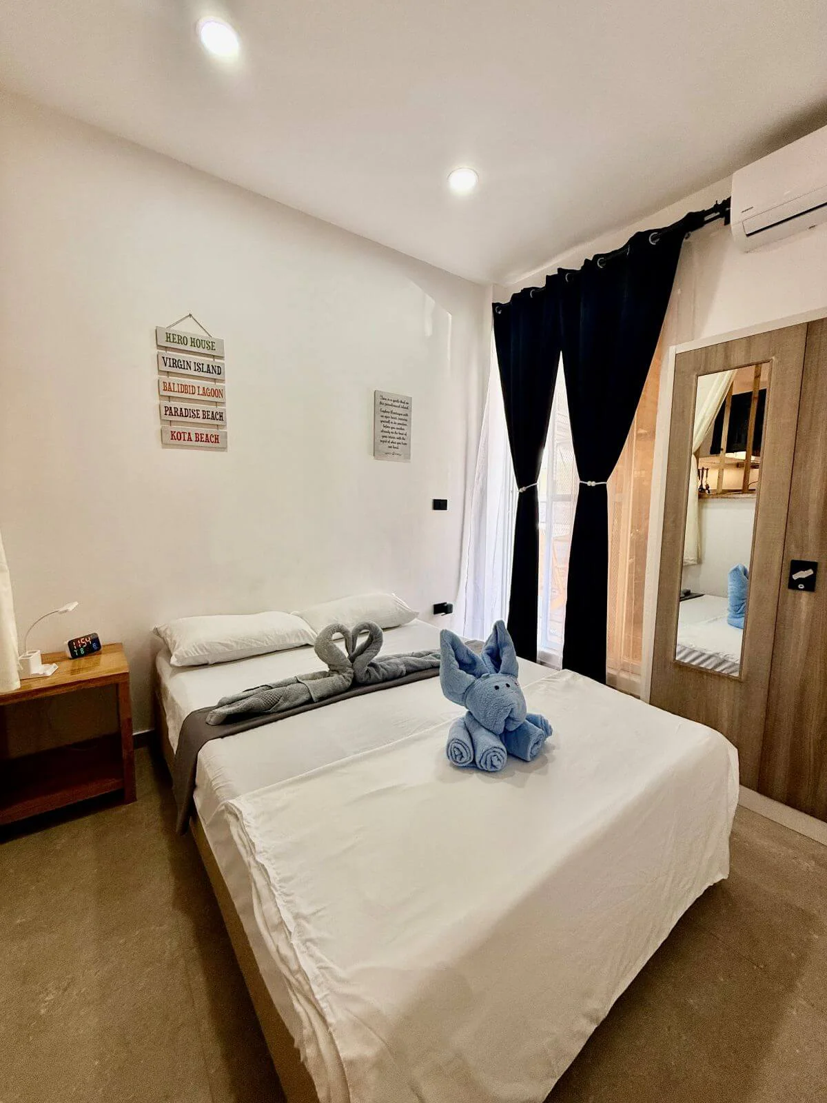 Bedroom with a wardrobe and a nightstand, and towel designs on the bed.