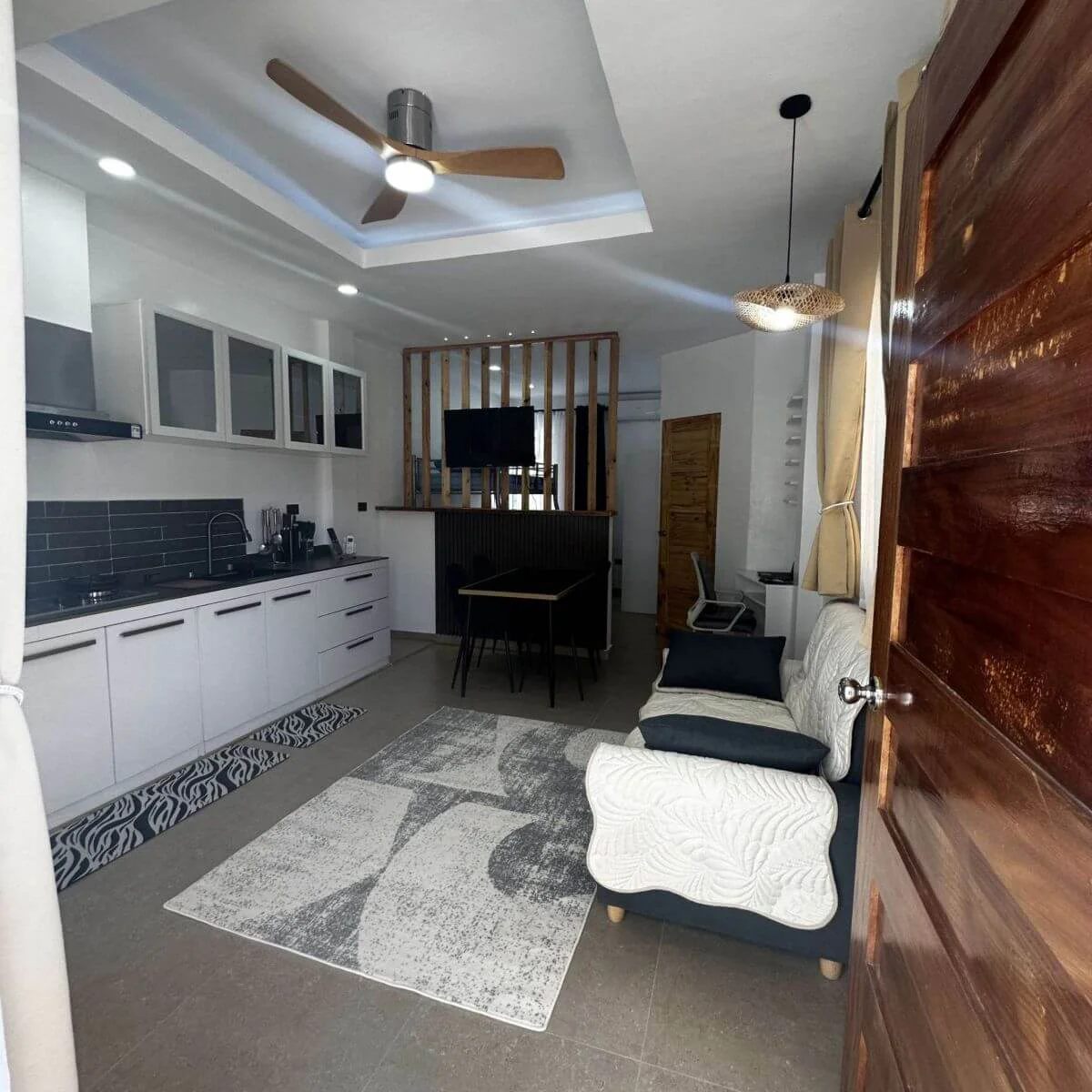 Spacious open-plan kitchen with a refrigerator and sofas with door at the Hero House Bantayan Mango apartment.