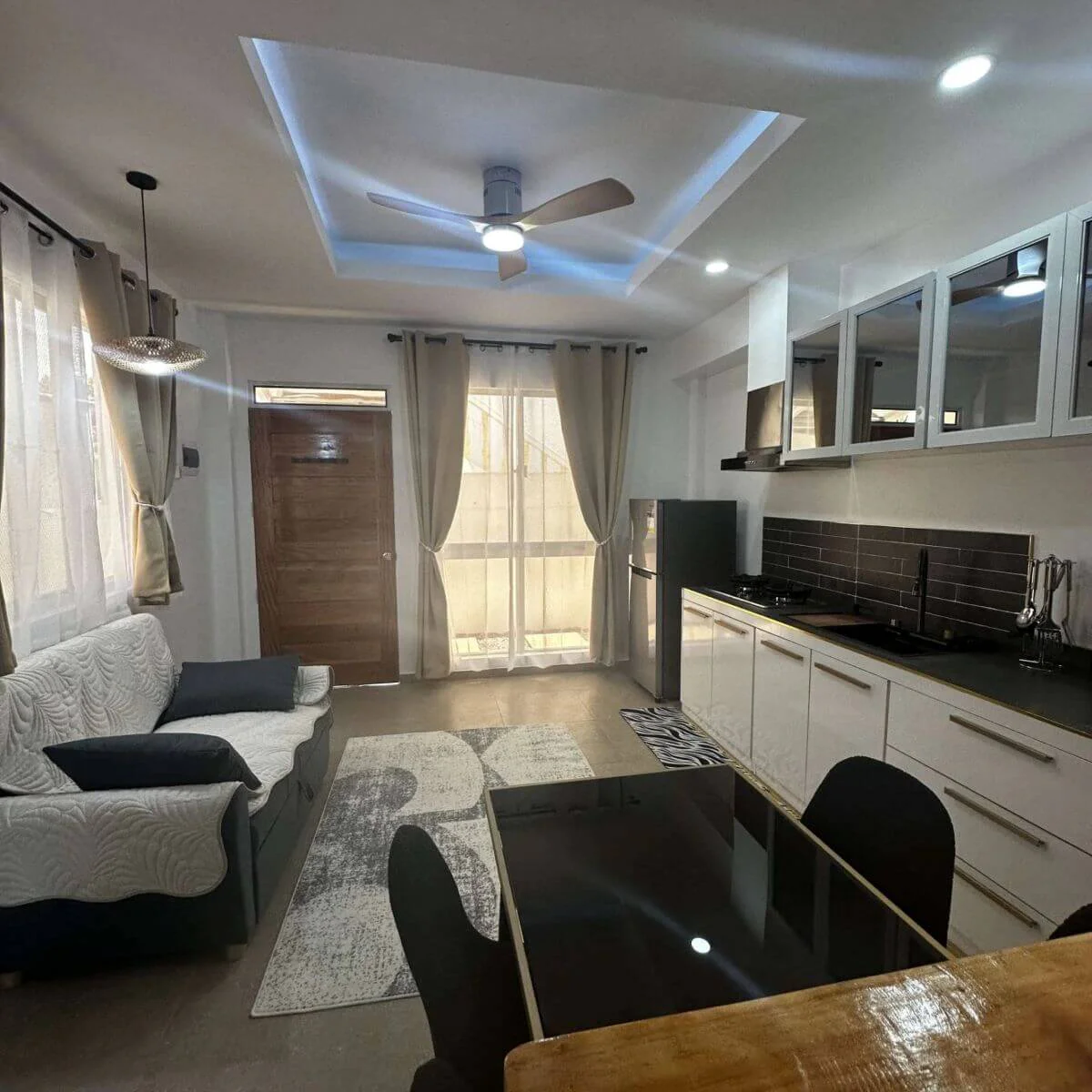 Spacious open-plan kitchen with a refrigerator and sofas at the Hero House Bantayan Mango apartment.