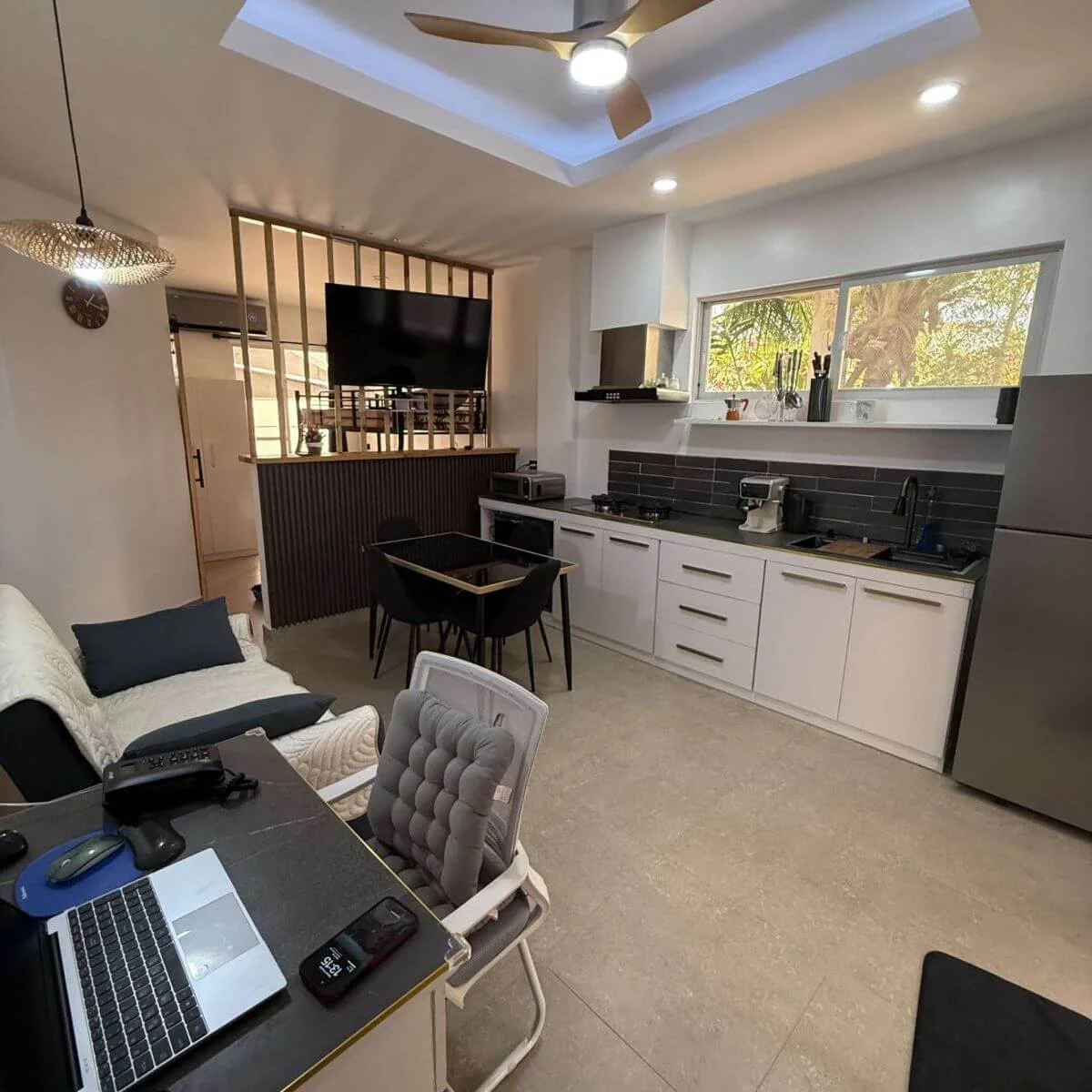 Spacious open-plan kitchen with a refrigerator and sofas and Table for digital Nomad at the Hero House Bantayan Papaya apartment.